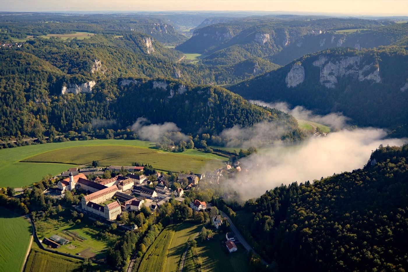Steile Felsen säumen die noch junge Donau bei Beuron. Im Vordergrund das Benediktinerkloster Erzabtei St. Martin. © Reiner Enkelmann