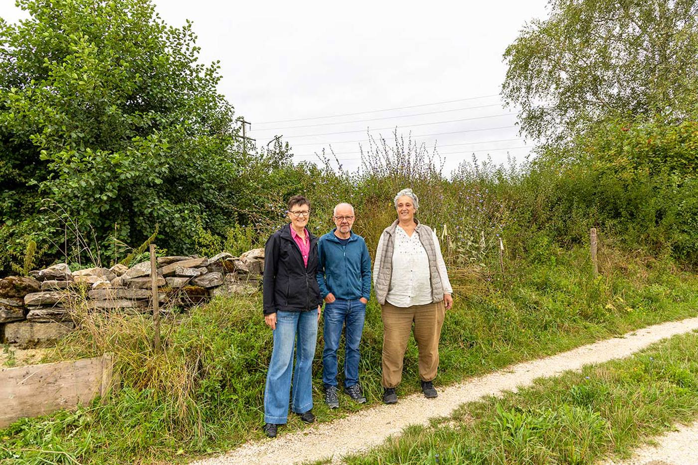 Ines Bill, Ernst Steiner und Claudia Kuhnert (v.l.) vor dem Baum- und Strauchlehrpfad Chrümmlisbach. An dieser Stelle hat der NVB zusammen mit Kindern ein Sandarium errichtet und Wildstauden gepflanzt. © Dario Pollice/BirdLife Schweiz